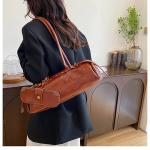 Detail view of brown cylinder shoulder bag with retro cracked leather texture and mini pouch