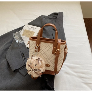 Detailed view of beige checkered handbag with brown leather trim and cute bunny charm