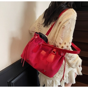 Detail of red suede tote bag with leather straps and drawstring on indoor staircase