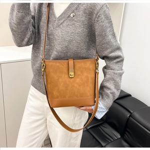 Detail view of a vintage bucket bag in tan faux suede with gold metal buckle closure