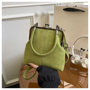 Macro view of green suede shell bag featuring vintage metal clasp and top handle details