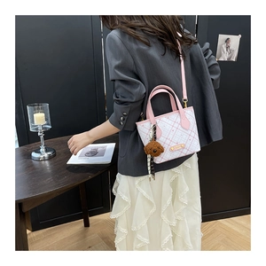 Detail of pink and white checkered bucket bag with cute teddy bear charm and metal logo