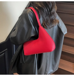 Rear view of red pebbled leather moon bag on a model wearing a black leather jacket