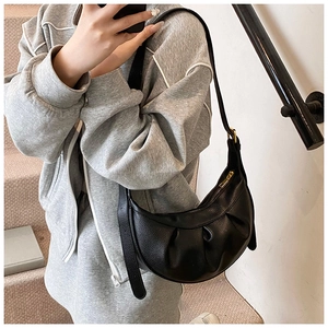 Détail d'un sac bandoulière en cuir grainé noir avec plis élégants et finitions dorées