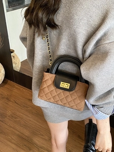 Brown quilted crossbody bag with gold lock and chain strap carried by a model