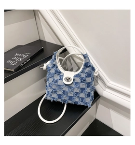 Close-up of blue and white checkered denim bucket bag featuring distressed fringe edges