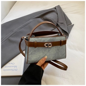 Detail showing blue denim fabric and brown leather handle with metal swivel lock