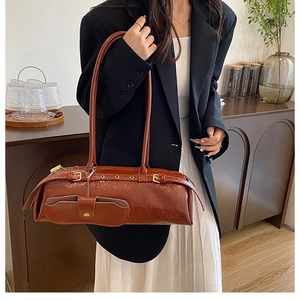 Retro brown cylinder shoulder bag in glossy wax leather featuring side pocket and gold buckle