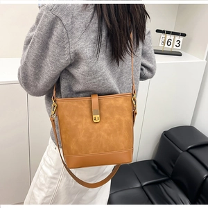 Detail of brown bucket bag featuring suede texture and smooth leather patchwork