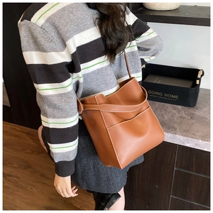 Close-up of brown bucket bag with white contrast stitching and long shoulder strap detail