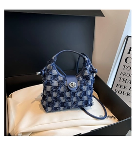 Close-up of checkered denim bucket bag featuring frayed edges and silver twist lock