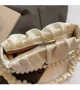 Gros plan d'un sac nuage plissé beige avec fermeture éclair et bandoulière perle