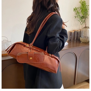 Detail of brown pleated patent leather shoulder bag with small buckle pouch accessory