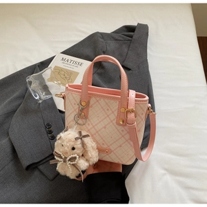 Detail of pink plaid handbag with plush bunny charm and adjustable shoulder strap