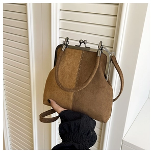 Detail of vintage suede shell bag with metal frame closure and decorative stitching