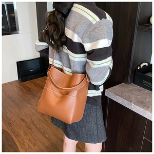 Brown leather bucket bag with white contrast stitching detail and long strap