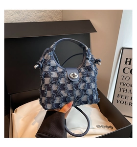 Detail of blue plaid denim bucket bag showing tassel edges and silver twist lock buckle