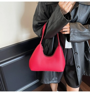 Detailed view of red lychee grain leather hobo bag worn with a black leather jacket