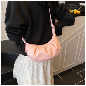 Vue détaillée latérale d'un sac bandoulière rose plissé en cuir avec texture litchi