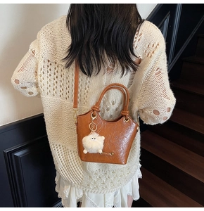 Close-up of vintage brown leather bucket bag with retro texture and plush charm