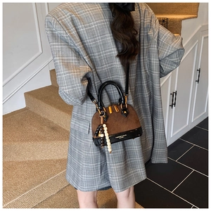 Retro quilted shell bag with beaded charm accessory shown in a stylish street style pose