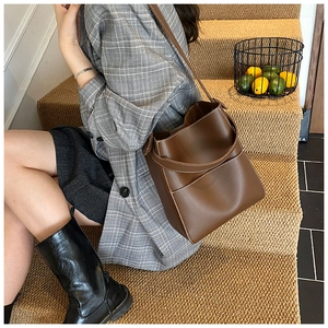 Detailed view of a brown bucket bag with contrast white stitching on leather surface