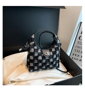 Detail view of denim checkerboard bucket bag with metal twist lock and fringe texture