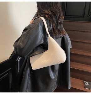 Detail of off-white lychee texture leather shoulder bag worn under the arm with sleek design