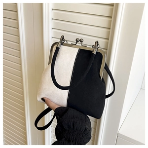 Detail showing the metal kiss-lock closure and elegant bicolored suede texture