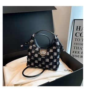 Detailed view of checkered denim bucket bag with frayed edges in a luxury gift box