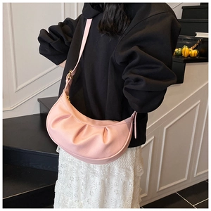Sac hobo demi-lune en cuir plissé rose présenté lors d'une séance photo mode