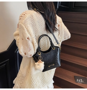 Close-up of black wrinkled faux leather bucket bag with a cute white lamb charm