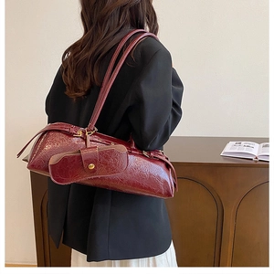 Detail of burgundy glossy leather shoulder bag with matching glasses pouch and metal button