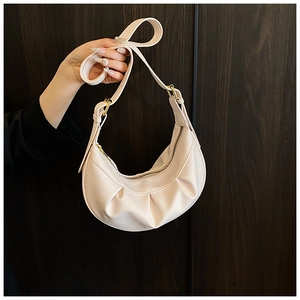 Détail du sac croissant crème avec texture cuir litchi et boucle métallique dorée