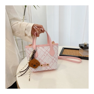 Detail of pink plaid bucket bag with plush dog charm and adjustable shoulder strap
