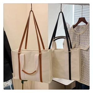Detail of canvas tote bags with leather-like handles in brown and black finishes