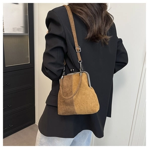 Detail of vintage kiss-lock closure and dual-tone brown suede textured crossbody bag