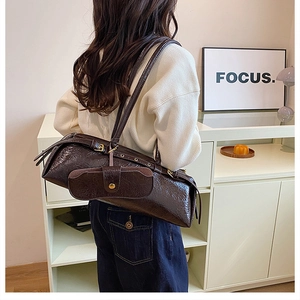 Brown vintage baguette bag with small pouch shown on model in a cozy indoor setting
