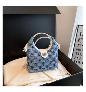 Detail of blue plaid denim bucket bag featuring frayed edges and silver twist lock closure