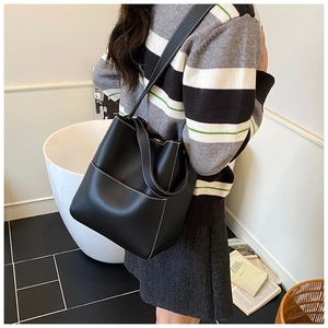 Detail showing black bucket bag with white contrast stitching and long shoulder strap