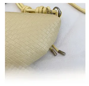 Dettaglio ravvicinato della borsa intrecciata in pelle giallo chiaro con inserti in metallo