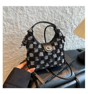 Close-up of black and white checkered tweed bucket bag with leather handle and silver lock