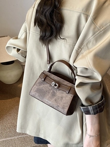 Vintage brown structured crossbody bucket bag shown on a model in a cozy interior setting