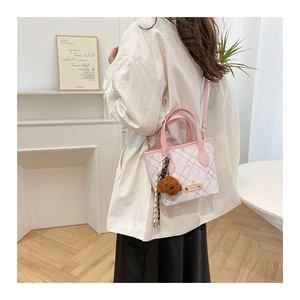 Pink and white checkered bucket bag styled with a plush bear charm on a female model