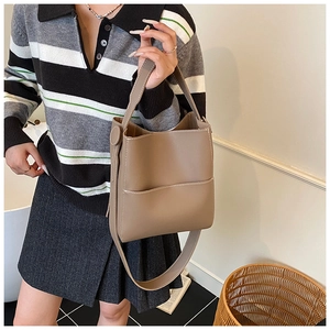 Detail of brown bucket bag showing contrast stitching, top handle and adjustable strap