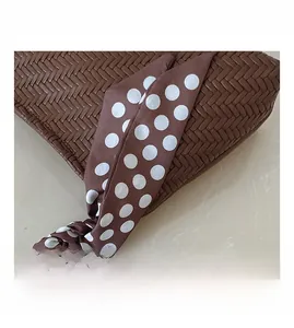 Detail of dark brown woven texture handbag with a polka dot silk scarf accent