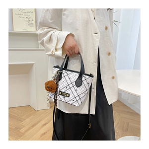 Detail of checkered bucket bag with metal logo, adjustable strap and plush bear charm