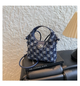 Detail of blue plaid denim bucket bag with frayed edges on a decorative book