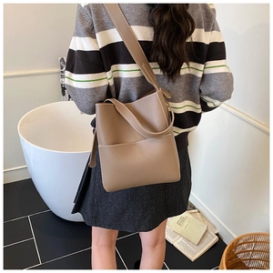 Detail of khaki leather bucket bag with white contrast stitching on wide shoulder strap