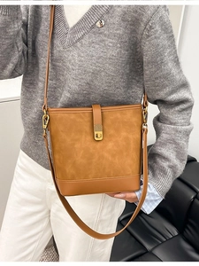 Chic brown bucket bag in matte leather finish with gold hardware and long strap